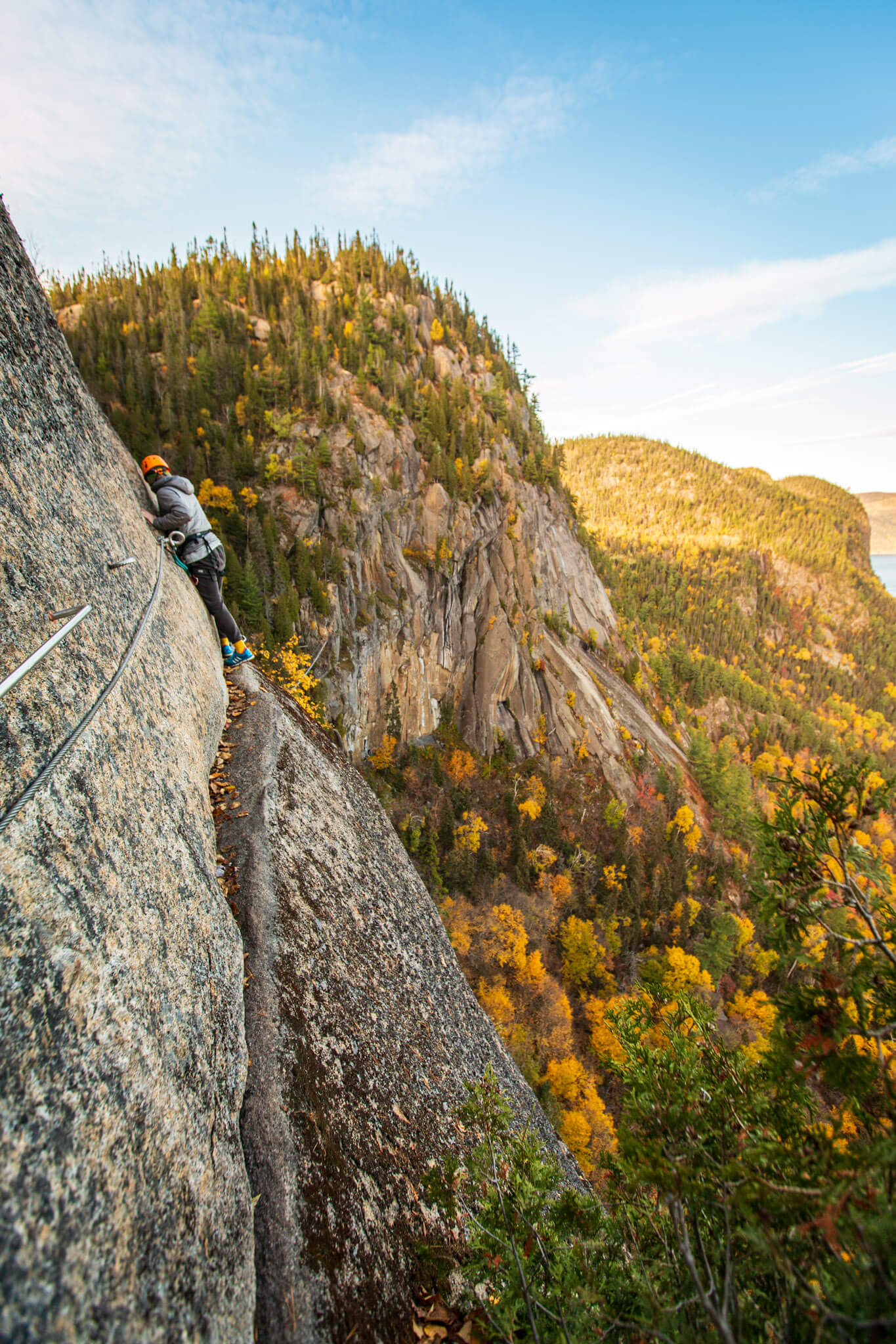 A rock climbers clings to the wall along a via ferrata route in the Saguenay Fjord National Park