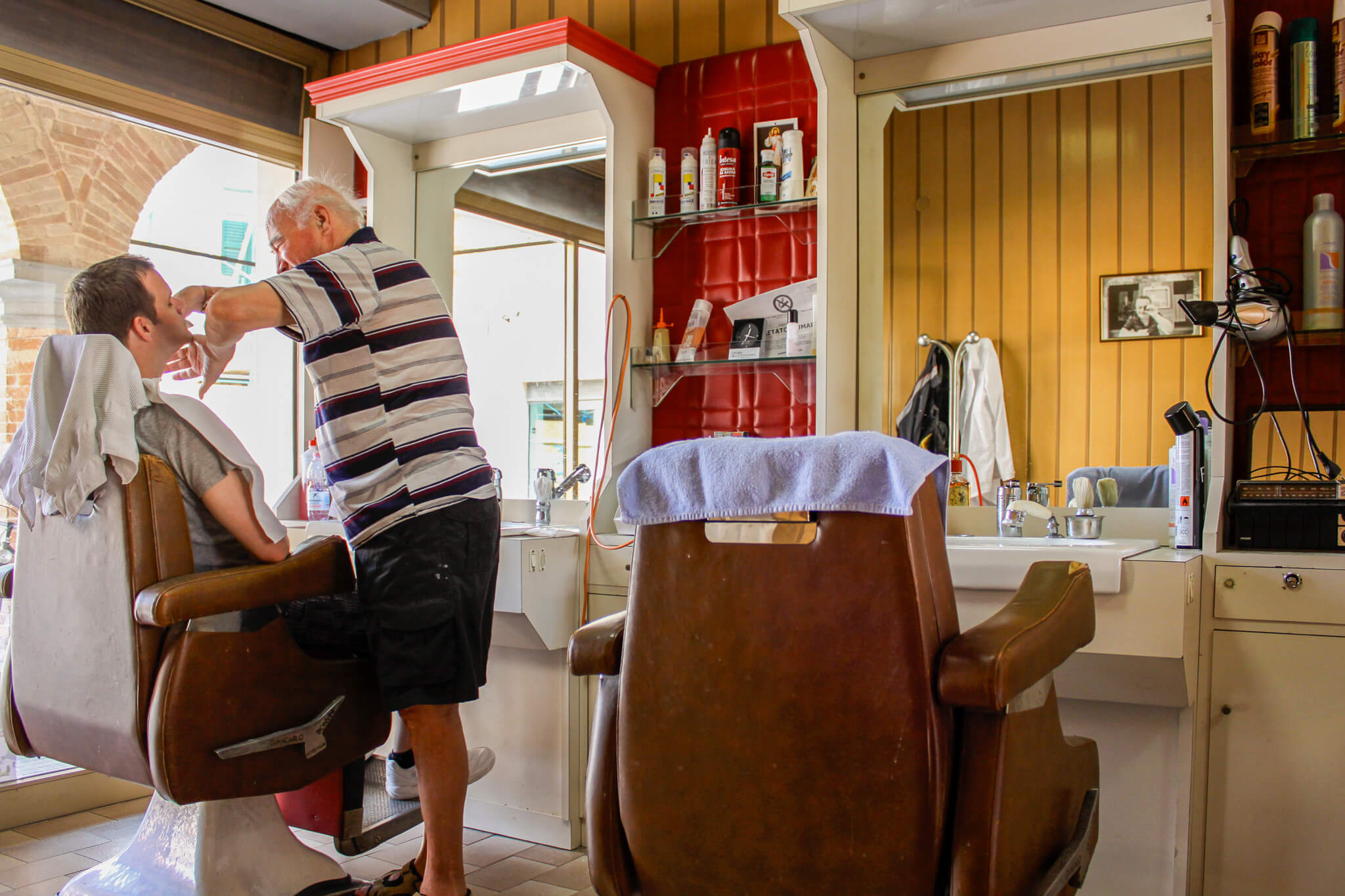 Getting a shave from a barber in Urbania, Italy