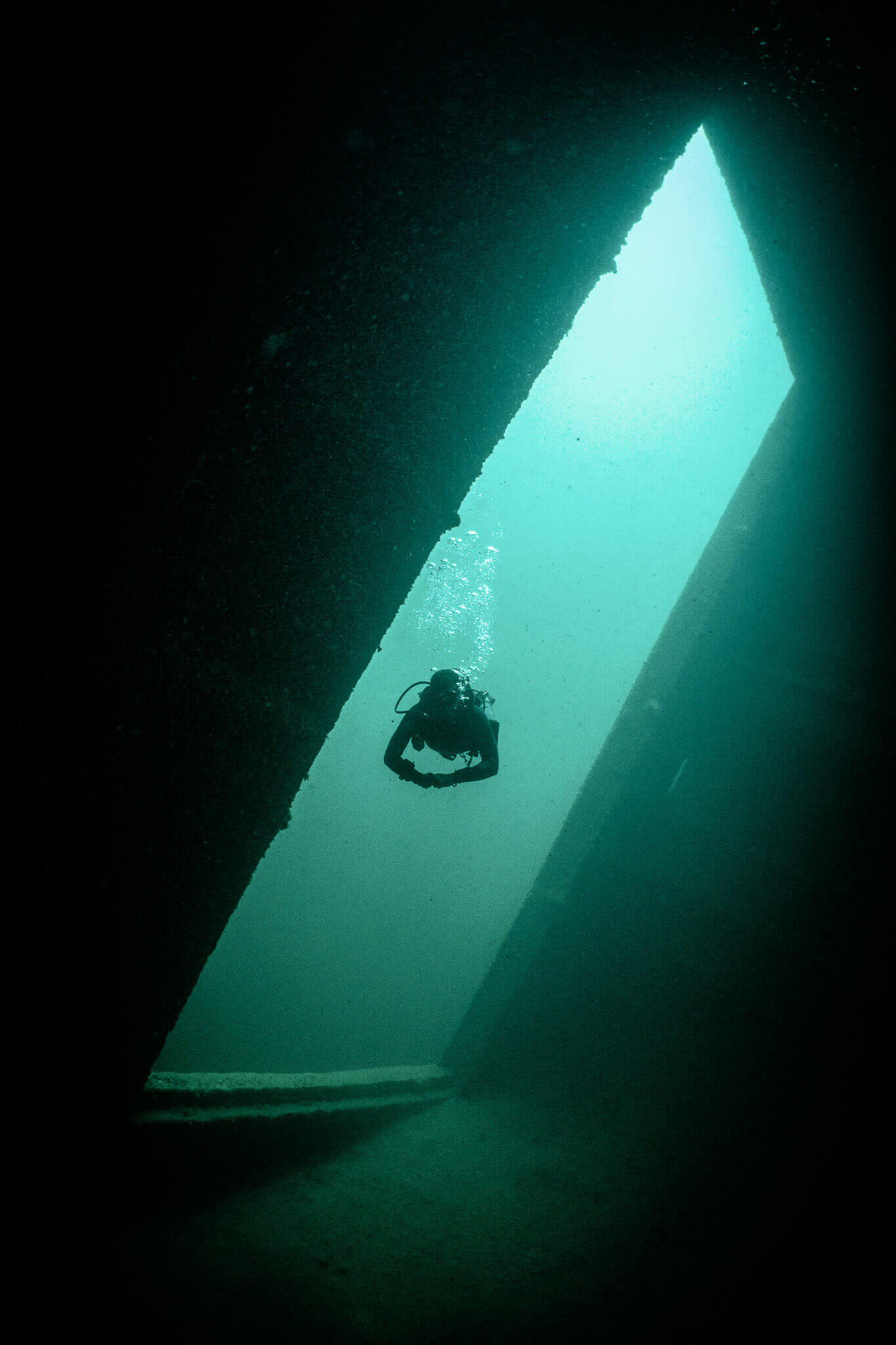Underwater photo of a scuba diver seen through a cargo hold on the Keystorm shipwreck