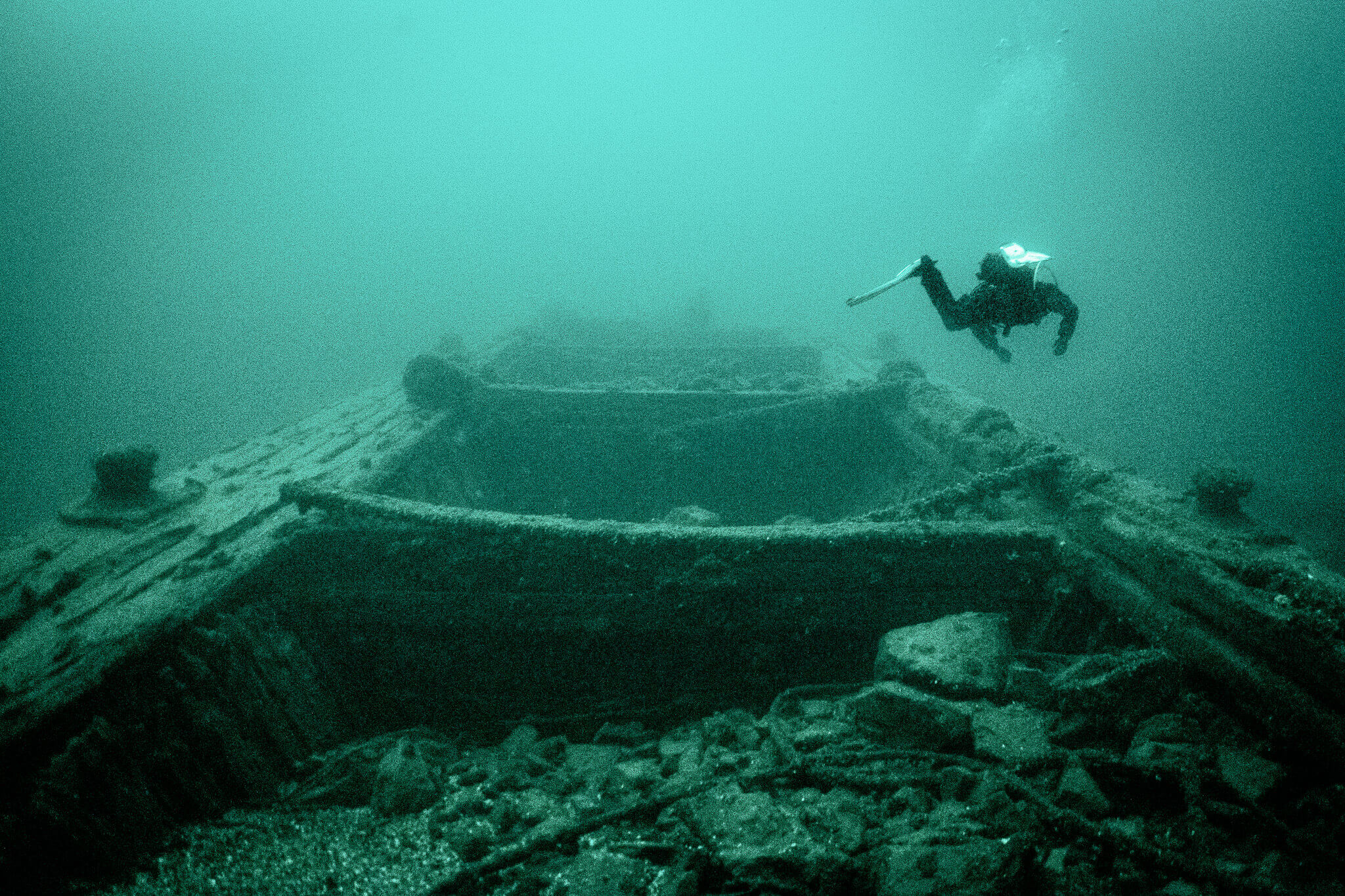 Underwater photo of a scuba diver exploring the Ash Island Barge shipwreck in the Thousand Islands area of the St. Lawrence River