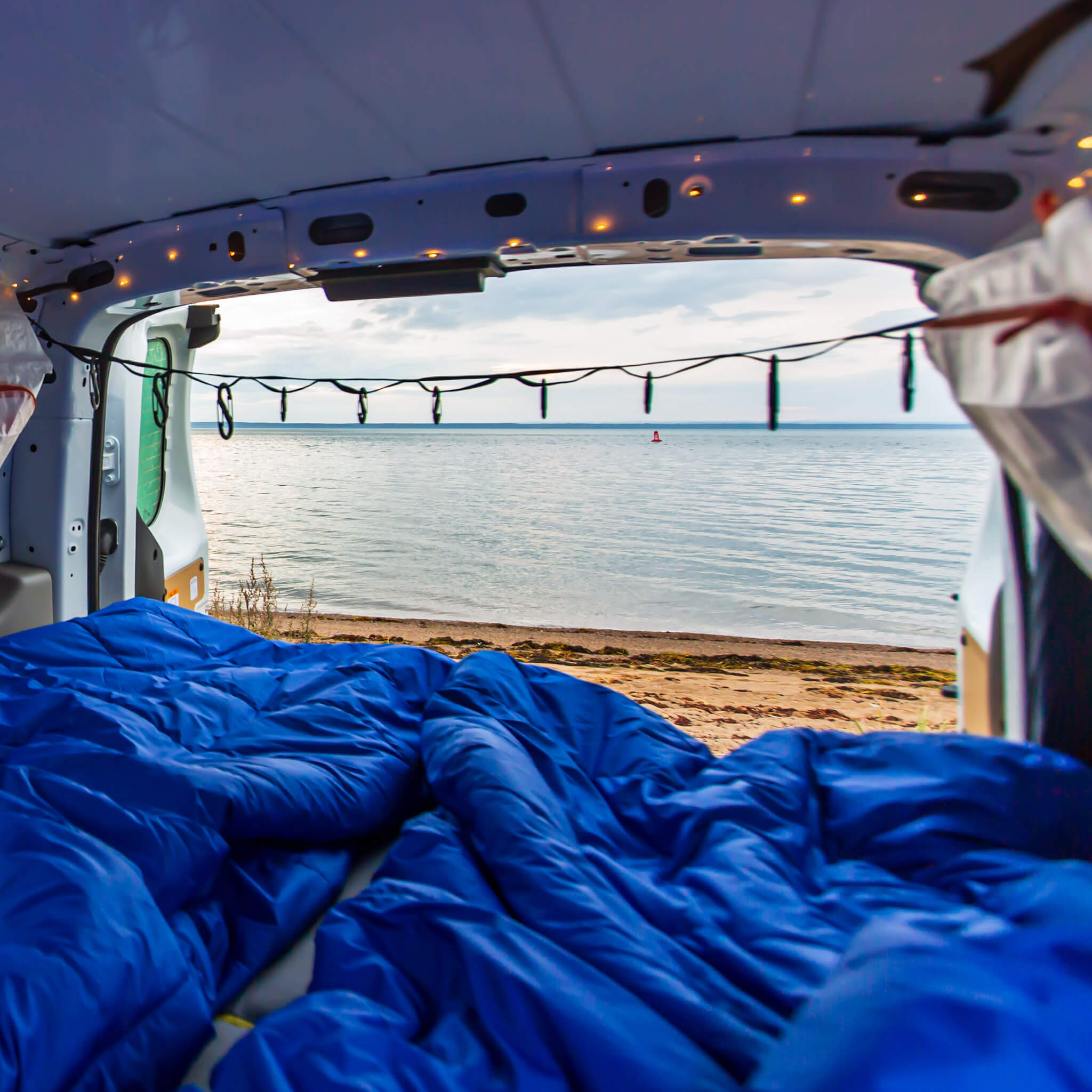 View of the beach along the St. Lawrence river from the inside of a Transit Connect camper van conversion