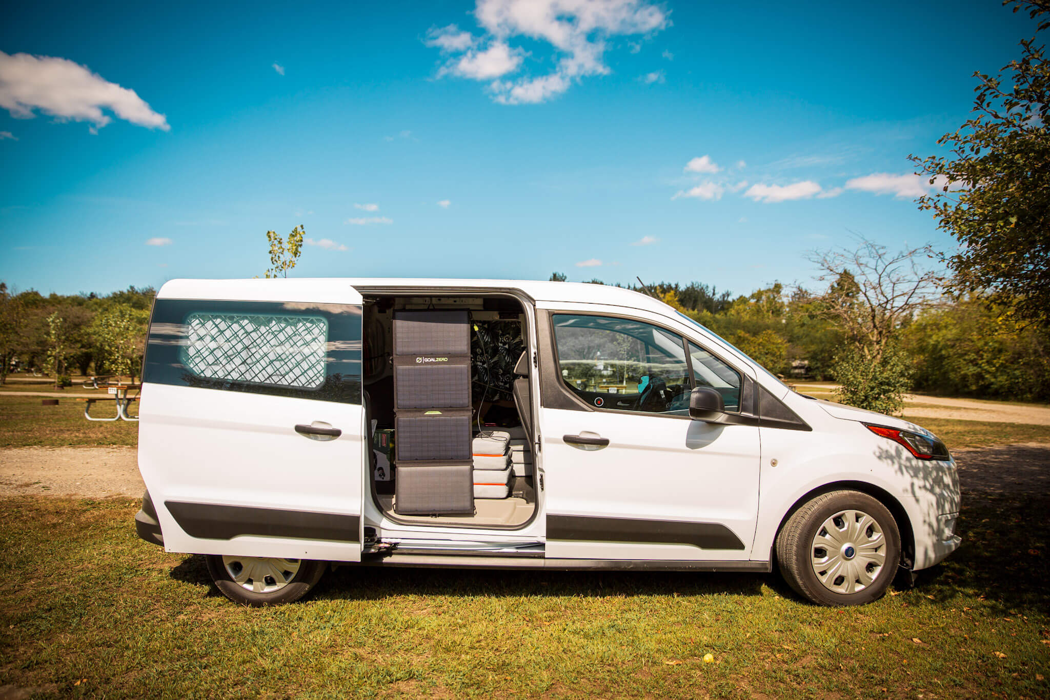 A Goal Zero Nomad 50 solar panel hangs in the side door of a compact cargo van