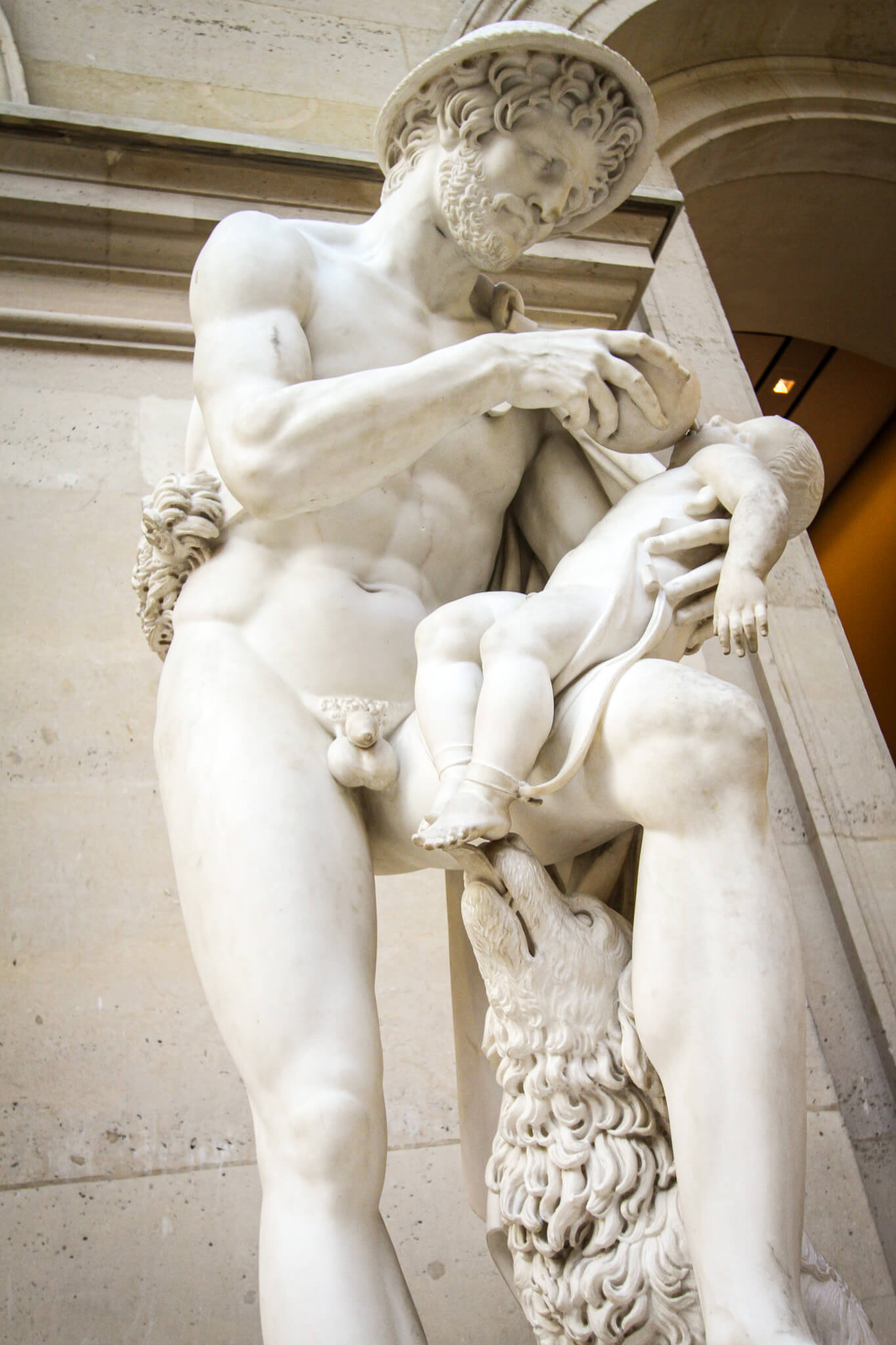 A statue of a shepherd holding a baby as a dog licks its toes, in the Louvre museum